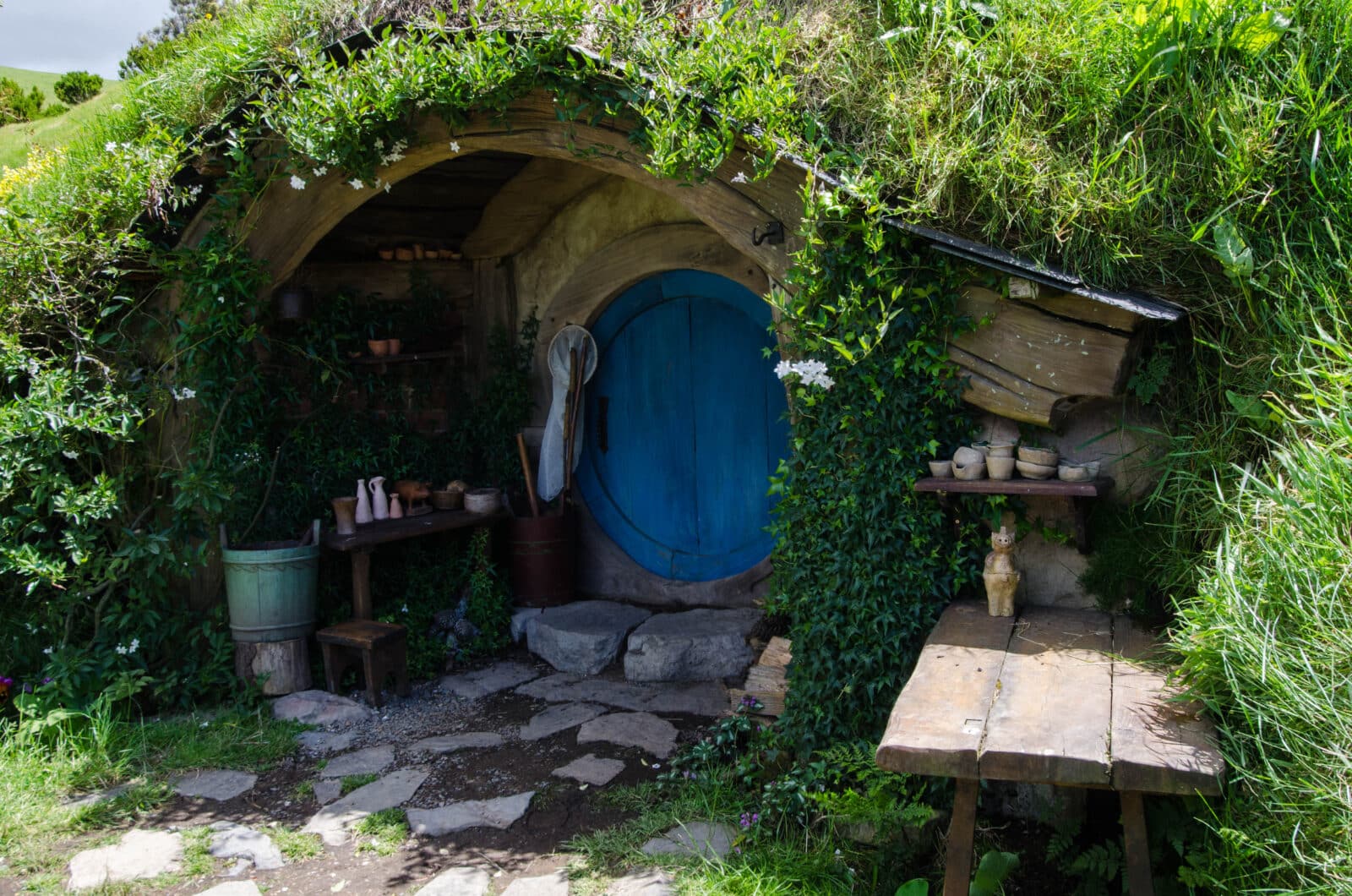 A round hobbit hole door surrounded by lush green grass at the Hobbiton movie set in New Zealand